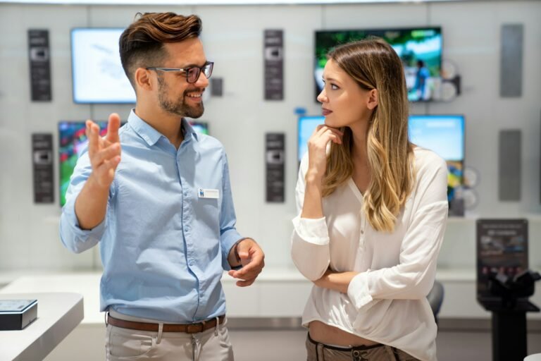 Happy people in consumer electronics retail store looking at new digital device